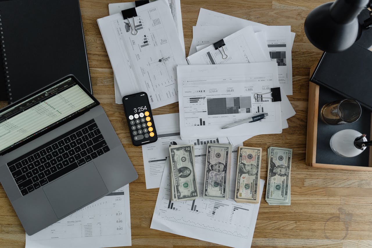 gallery-2 Overhead view of financial documents, cash, and technology on a wooden desk.
